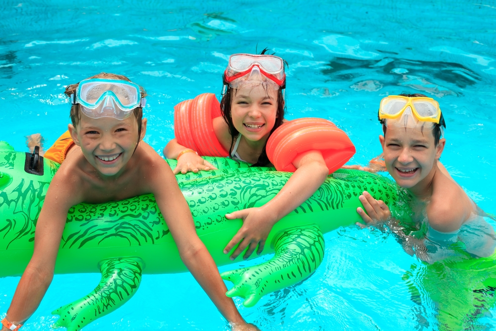 Igra otrok v bazenu z napihljivim krokodilom.