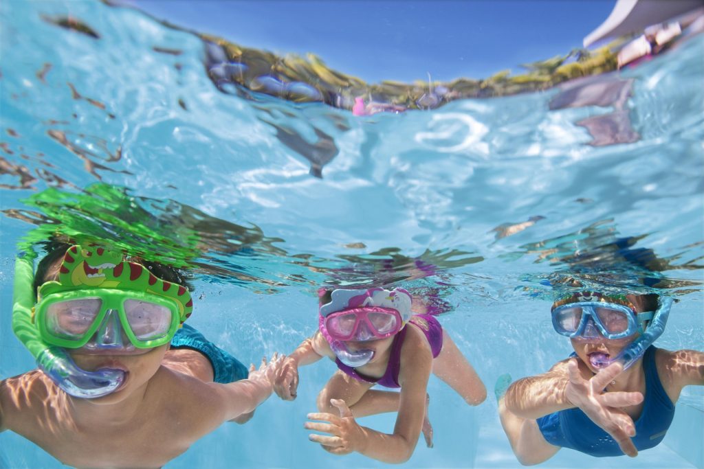 Trije otroci s plavalnimi maskami, slikani pod vodo v montažnem bazenu Bestway.